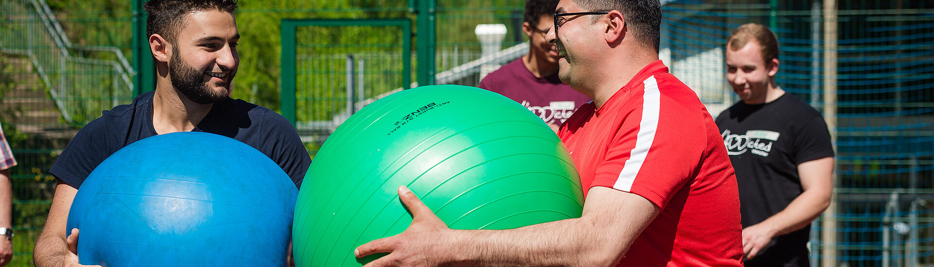 zwei sich gegenüberstehende Personen halten einen Gymnastikball in der Hand 
