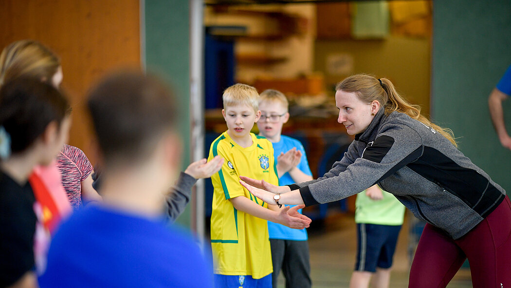 Eine Übungsleiterin spricht mit einer Gruppe Kinder